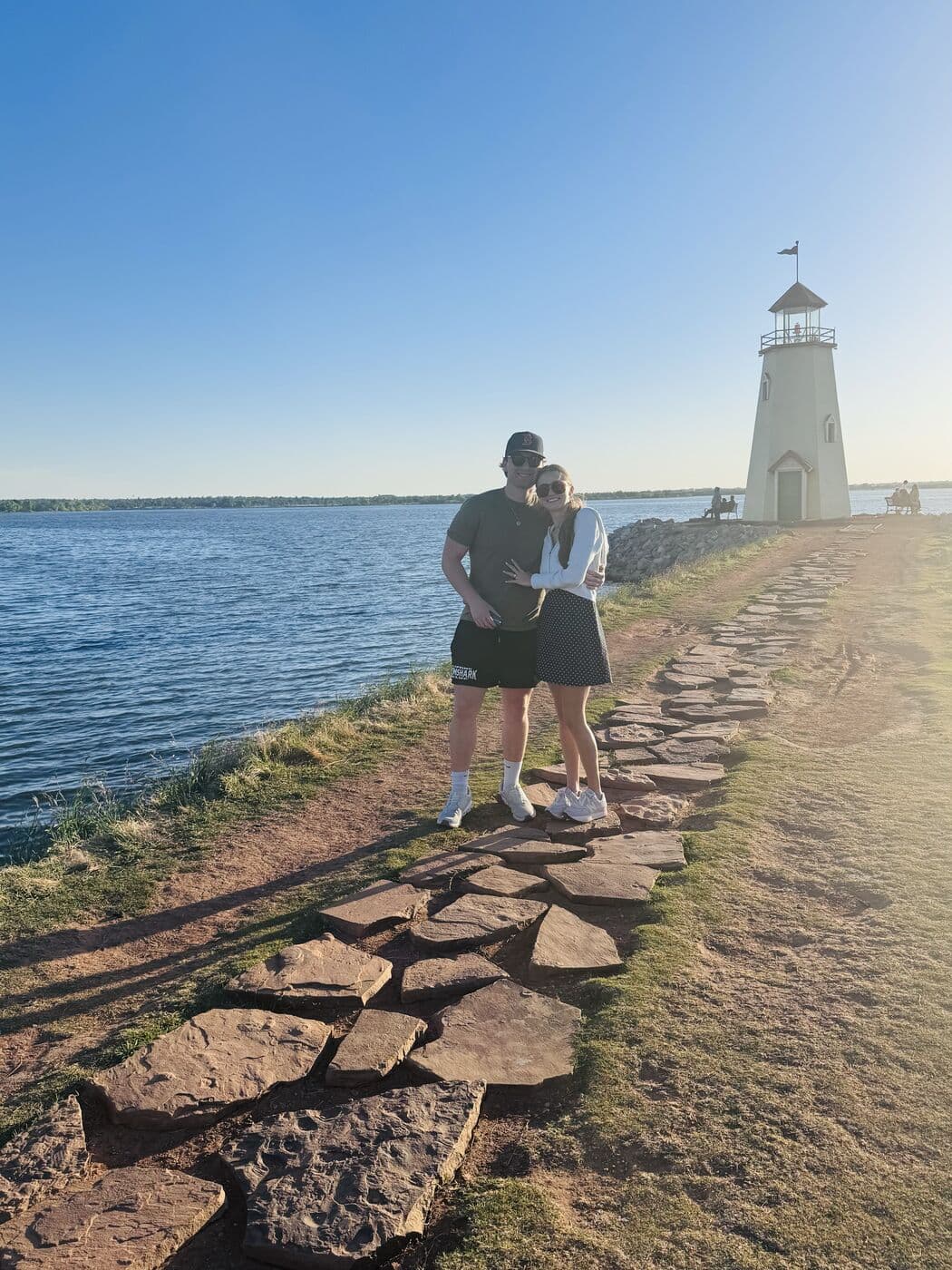 Elise and Tyler on the stone path along the water, the lighthouse behind them