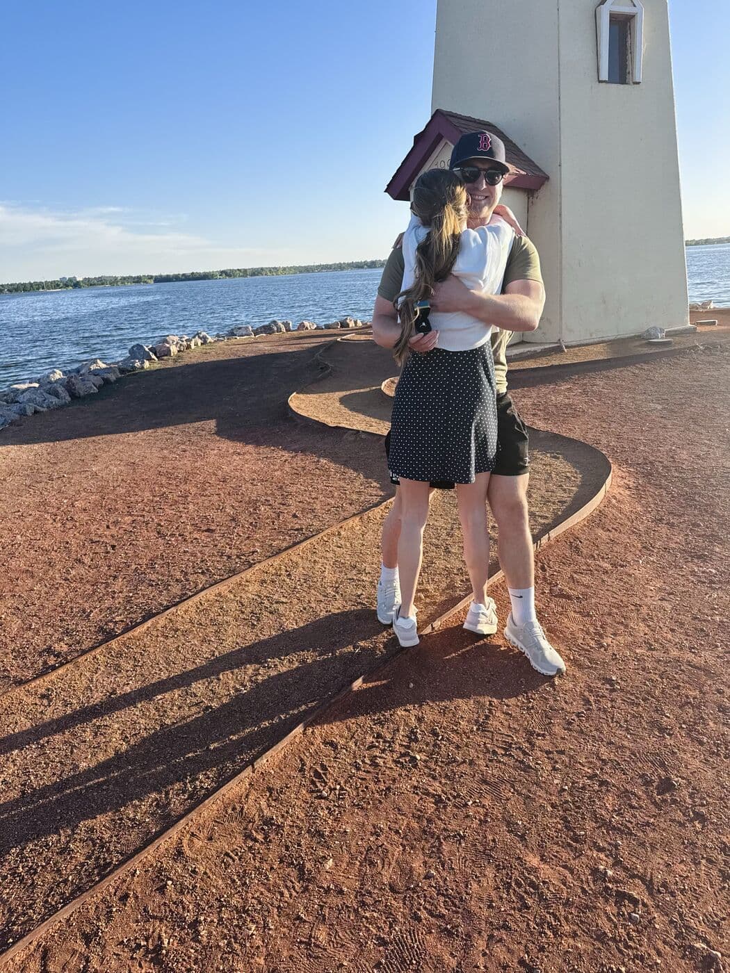Elise and Tyler holding each other at the foot of the lighthouse